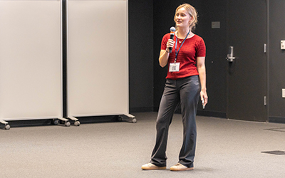 An undergraduate student in red and black presents a lightening talk at the MERCURY conference.